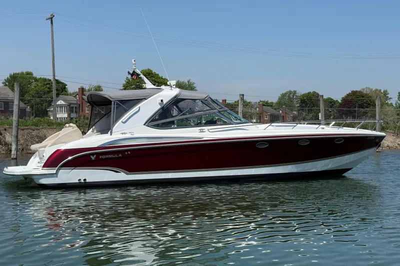 The Image of 2009 Formula 400 Super Sport boat on calm water, with a sleek red and white design. - 0