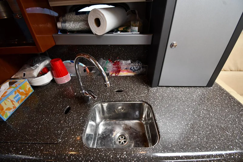 Slide: The Image of Kitchen sink area in a 2009 Formula 400 Super Sport boat with countertop and storage. - 38