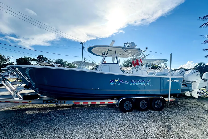 The Image of 2020 Regulator 34 boat on trailer, labeled "SIP-N-HOOK," under a clear blue sky. - 0
