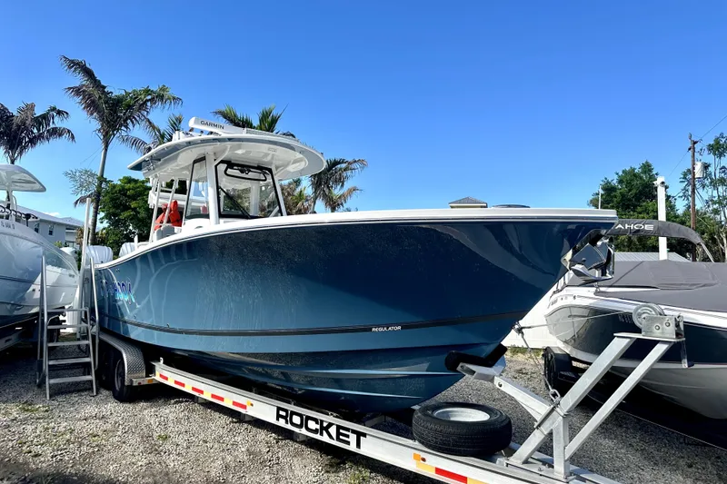 Slide: The Image of 2020 Regulator 34 boat on trailer, parked outdoors under clear blue sky. - 1