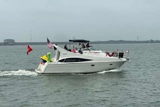 Slide: The Image of 2004 Carver 360 Mariner yacht cruising on a calm waterway, adorned with flags. - 1