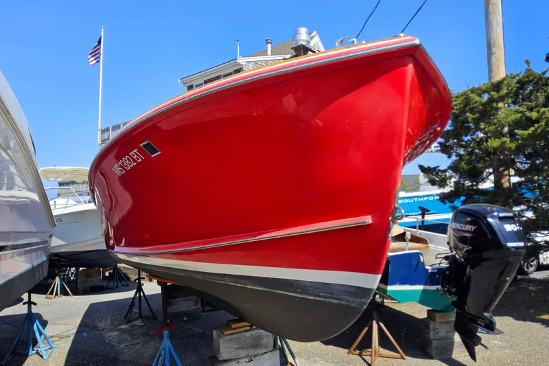 Slide: The Image of Red 2010 Grey Barn Boatworks North Shore 22 boat on stands, with American flag in background. - 2