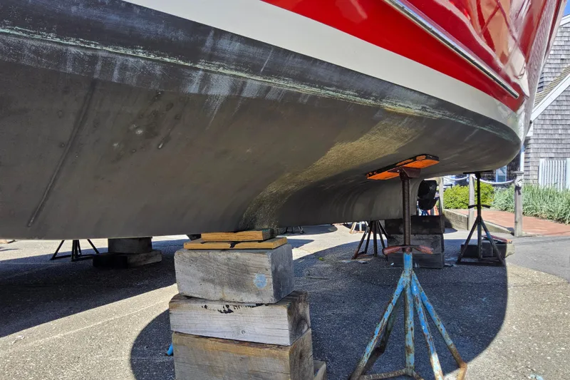 Slide: The Image of 2010 Grey Barn Boatworks North Shore 22 on stands, showing hull and red trim. - 20