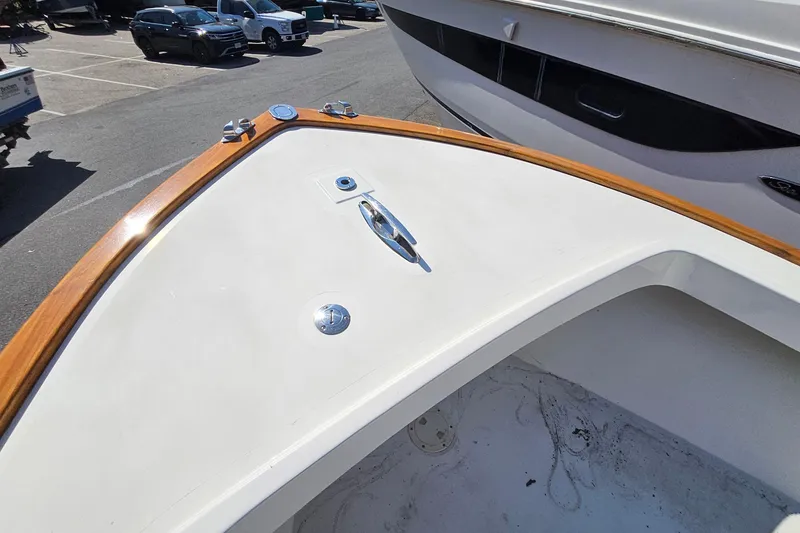 Slide: The Image of Bow of 2010 Grey Barn Boatworks North Shore 22 with wooden trim in a parking lot. - 6