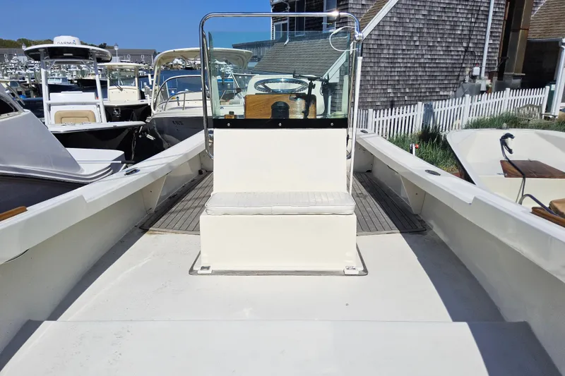 Slide: The Image of 2010 Grey Barn Boatworks North Shore 22, docked with other boats, featuring a central console. - 7