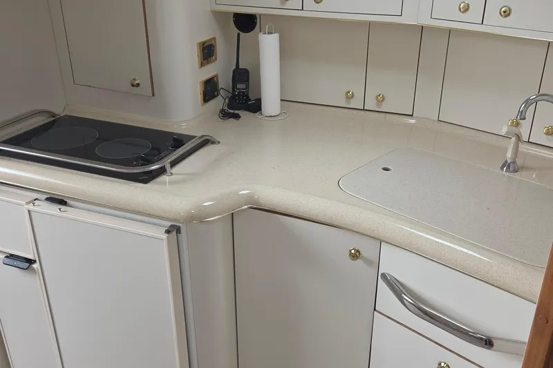 Slide: The Image of 1998 Sea Ray 370 Express Cruiser kitchen with stove, sink, and white cabinetry. - 18