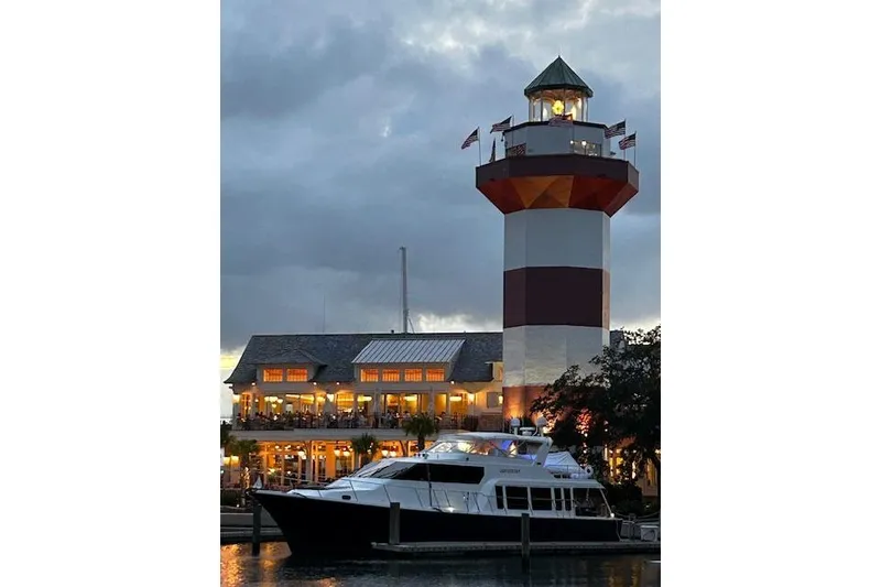 Slide: The Image of 2000 Pacific Mariner 65 Motoryacht docked near illuminated lighthouse at dusk. - 72