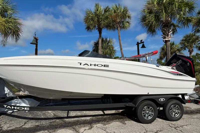The Image of 2026 Tahoe T21 boat on trailer, parked under palm trees, clear blue sky background. - 0