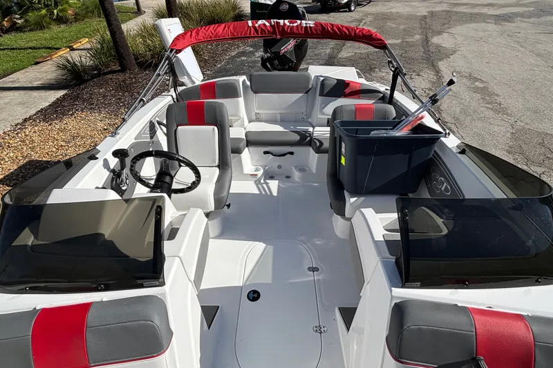 Slide: The Image of 2026 Tahoe T21 boat interior with red and gray seating, steering wheel, and storage bin. - 11
