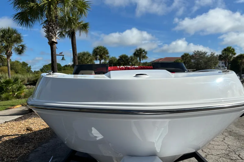 Slide: The Image of 2026 Tahoe T21 boat front view with palm trees and blue sky background. - 2