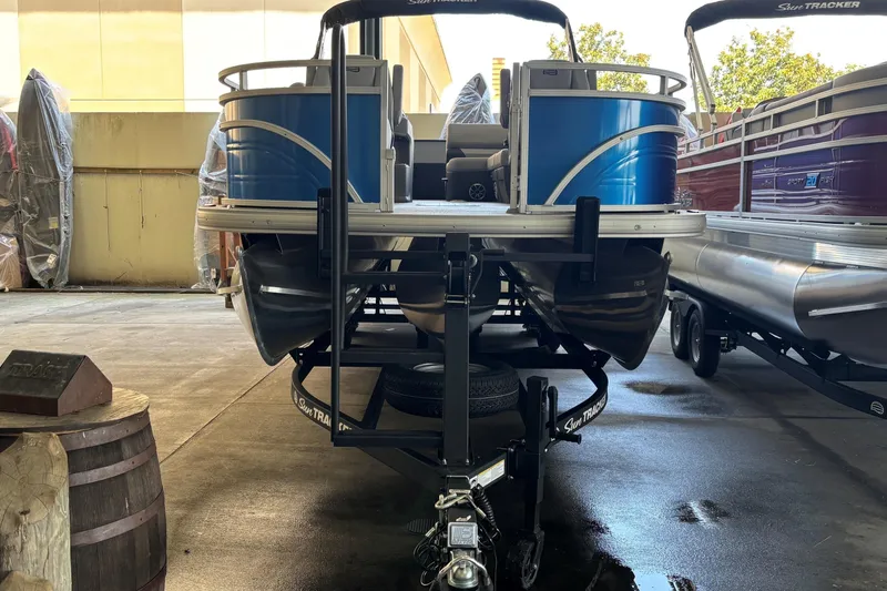 Slide: The Image of 2026 Sun Tracker Sportfish 24 XP3 pontoon boat on trailer in storage facility. - 1