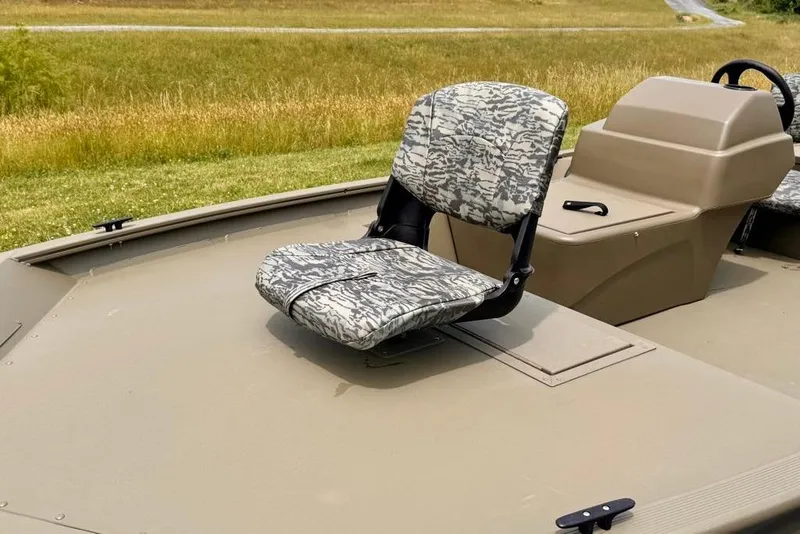 Slide: The Image of 2026 Tracker Grizzly 1754 SC boat with camo seat and console, in grassy landscape. - 10