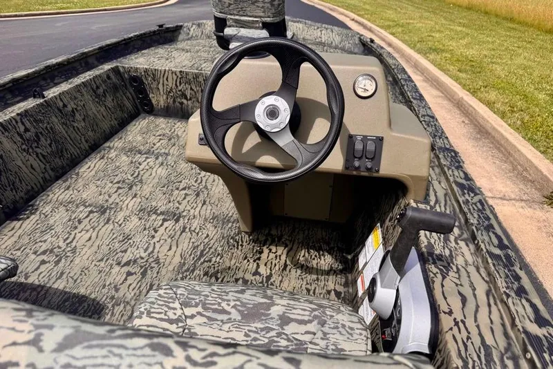 Slide: The Image of 2026 Tracker Grizzly 1754 SC boat interior with camouflage design and steering console. - 7