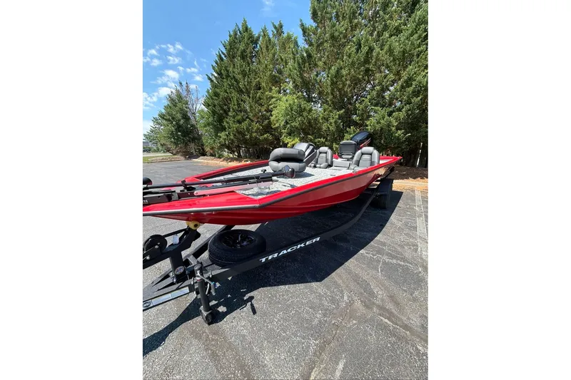The Image of Red 2026 Tracker Pro Team 195 boat on trailer, parked near trees under a clear sky. - 0
