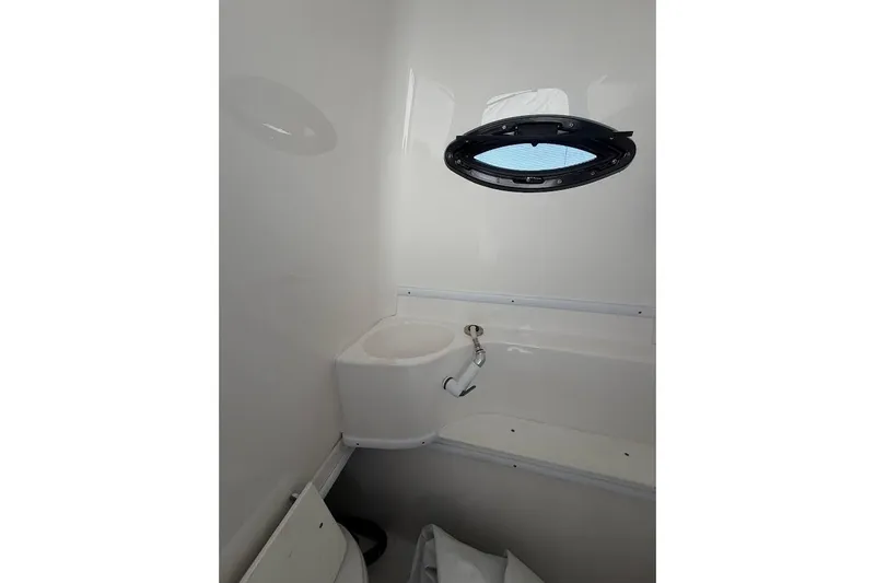 Slide: The Image of Compact boat bathroom with a small sink and oval window, Contender 2021 model. - 11