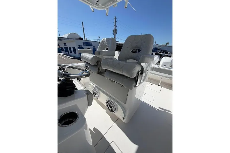 Slide: The Image of 2021 Contender boat with dual cushioned seats and steering wheel, docked under clear blue sky. - 12