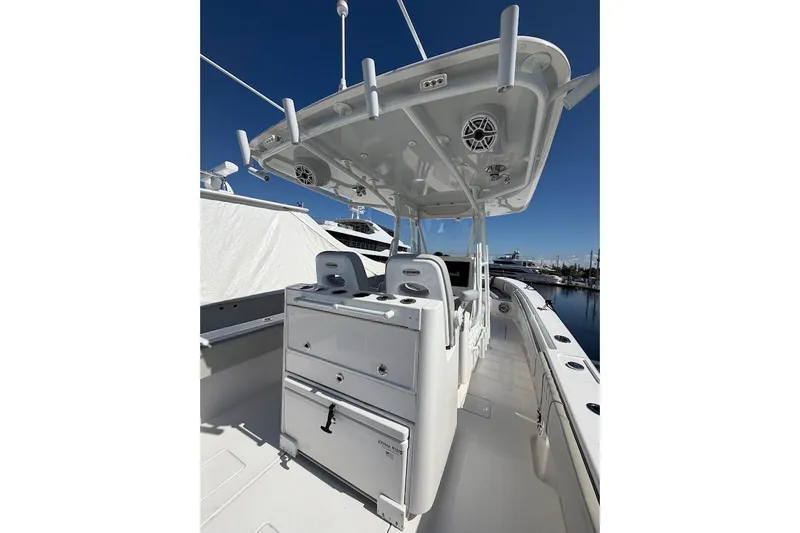 Slide: The Image of 2021 Contender boat with center console, rod holders, and seating, docked under clear blue sky. - 6