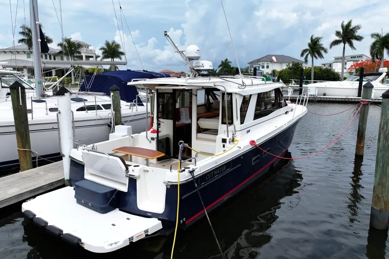 Slide: The Image of 2015 Cutwater 30 Sedan docked at marina, surrounded by palm trees and luxury boats. - 1