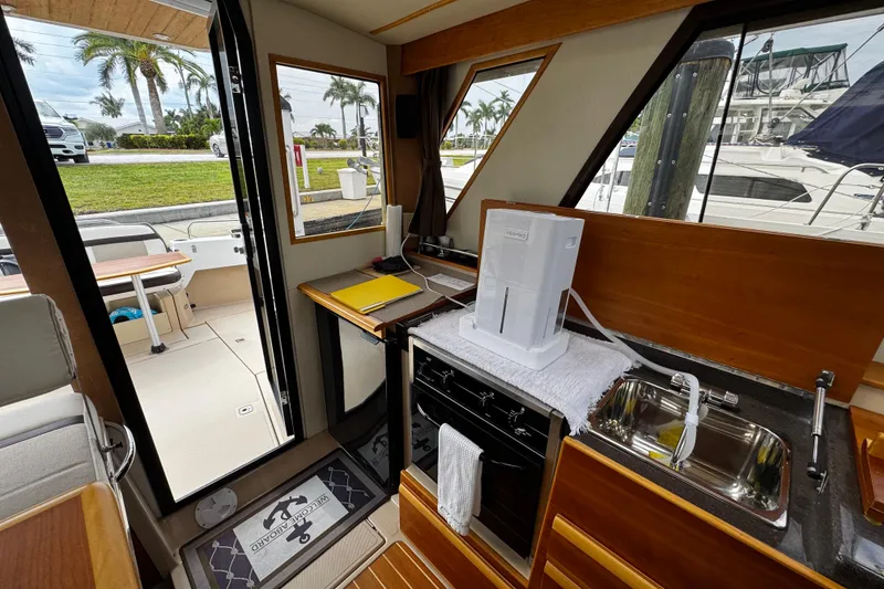 Slide: The Image of Interior of 2015 Cutwater 30 Sedan boat with kitchenette and outdoor view. - 11