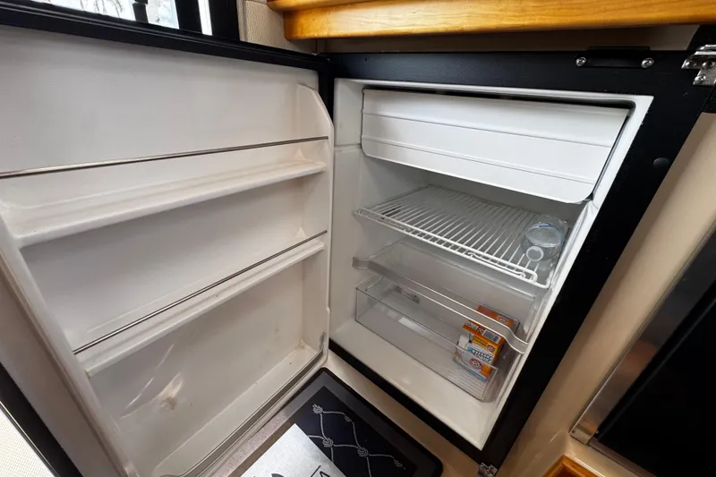 Slide: The Image of Open refrigerator inside 2015 Cutwater 30 Sedan boat, showing shelves and minimal contents. - 17