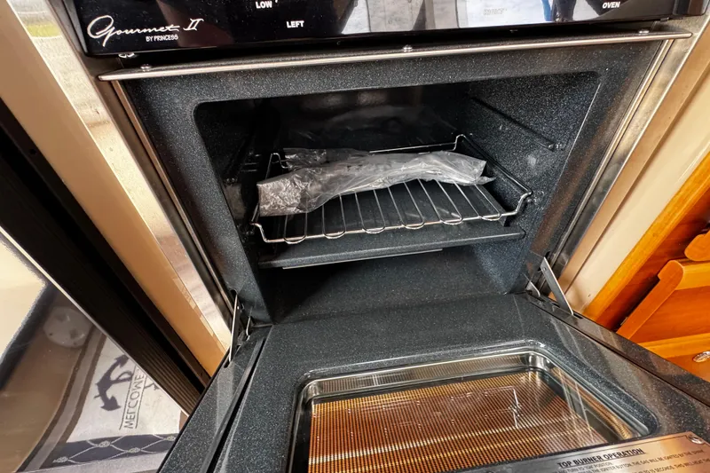 Slide: The Image of Open oven in a 2015 Cutwater 30 Sedan boat, showcasing interior with a wrapped item. - 18