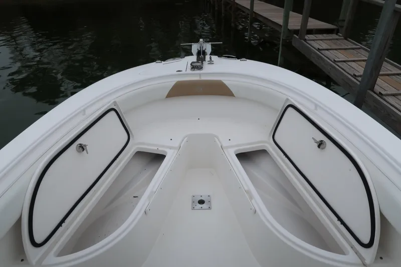 Slide: The Image of 2017 Edgewater 245CC boat bow with open storage compartments by a dock. - 13
