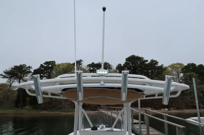 Slide: The Image of 2017 Edgewater 245CC boat with rod holders and antenna, docked near a wooded shoreline. - 5