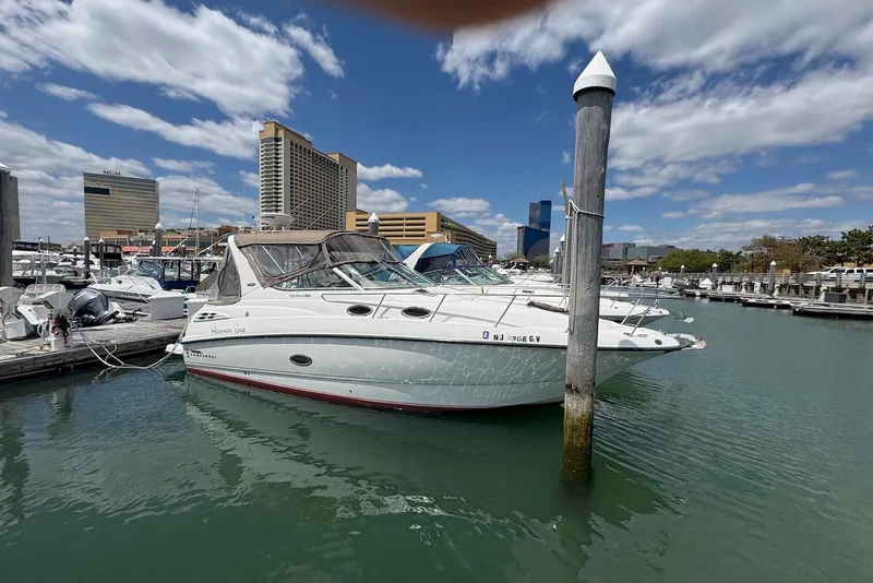 Slide: The Image of 1999 Chaparral Signature 300 boat docked in a marina with city skyline background. - 1