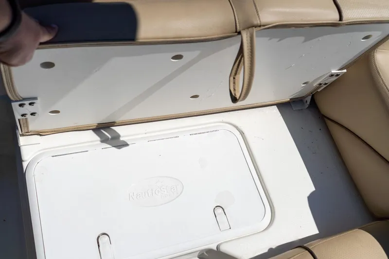 Slide: The Image of 2020 NauticStar 203 SC boat seat storage compartment with beige upholstery. - 17