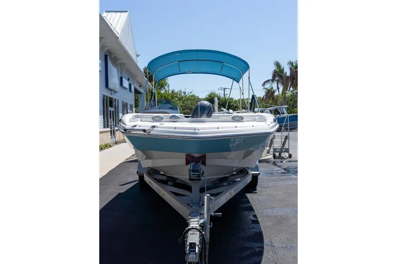 Slide: The Image of 2020 NauticStar 203 SC boat with blue canopy on trailer, parked outdoors. - 23