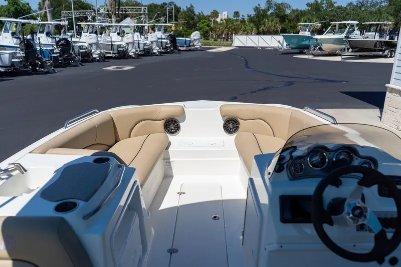 Slide: The Image of 2020 NauticStar 203 SC boat interior with beige seating and dashboard, parked in marina. - 25