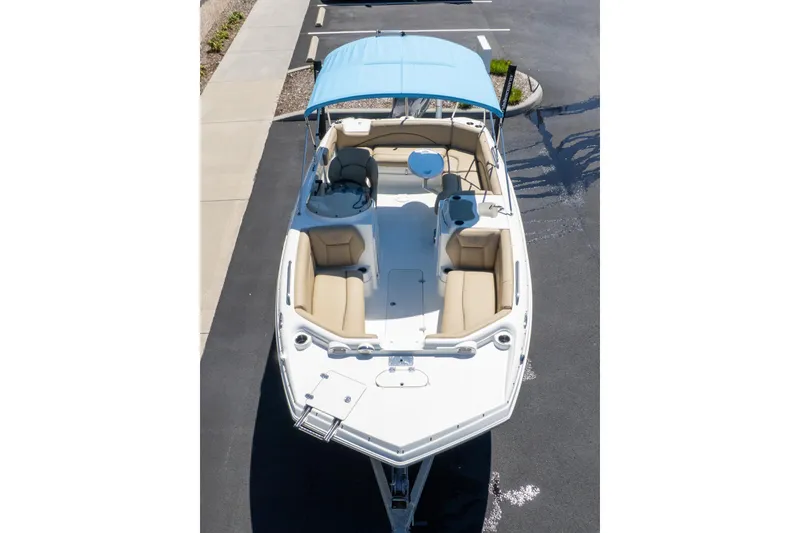 Slide: The Image of 2020 NauticStar 203 SC boat with blue canopy and beige seating, parked on pavement. - 5