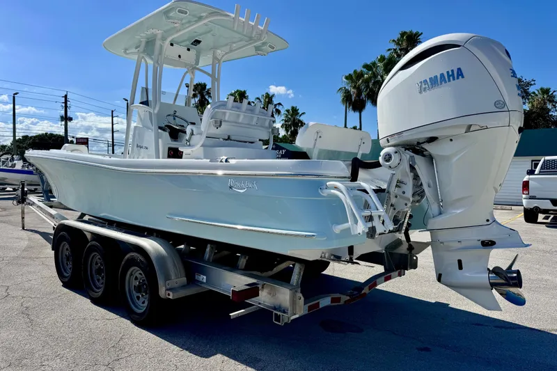 Slide: The Image of 2026 BlackJack 256 Coastal boat on trailer with Yamaha engine, parked outdoors. - 2