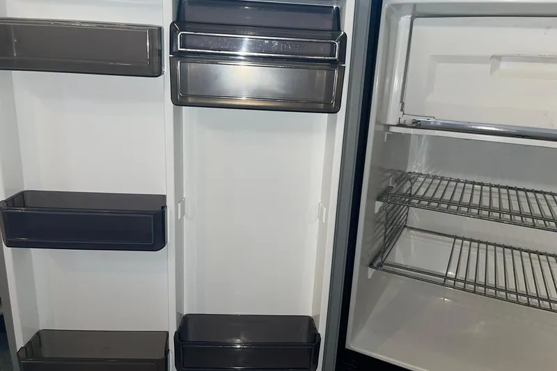 Slide: The Image of Empty refrigerator shelves and door compartments in a 1992 Sea Ray 370 Express Cruiser. - 11