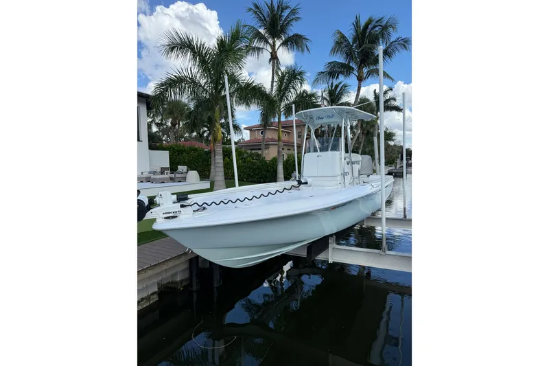 The Image of 2024 Contender 26 Bay boat on lift, surrounded by palm trees and waterfront homes. - 1