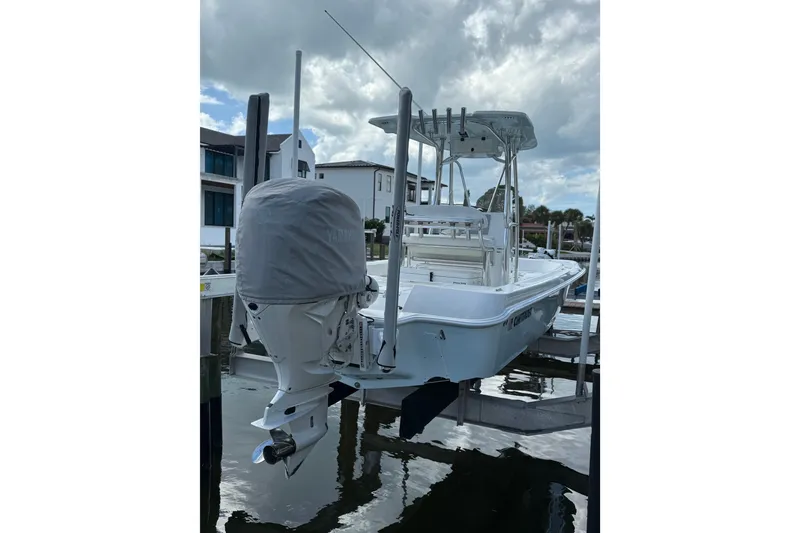Slide: The Image of 2024 Contender 26 Bay boat docked, featuring a covered outboard motor. - 10
