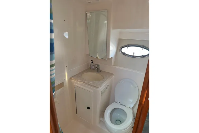 Slide: The Image of Bathroom interior of 2003 Tiara Yachts 3500 Open, featuring sink, toilet, and porthole window. - 15