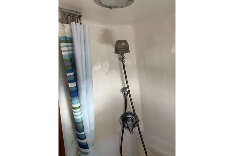 Slide: The Image of Shower area in 2003 Tiara Yachts 3500 Open, featuring striped curtain and handheld showerhead. - 16