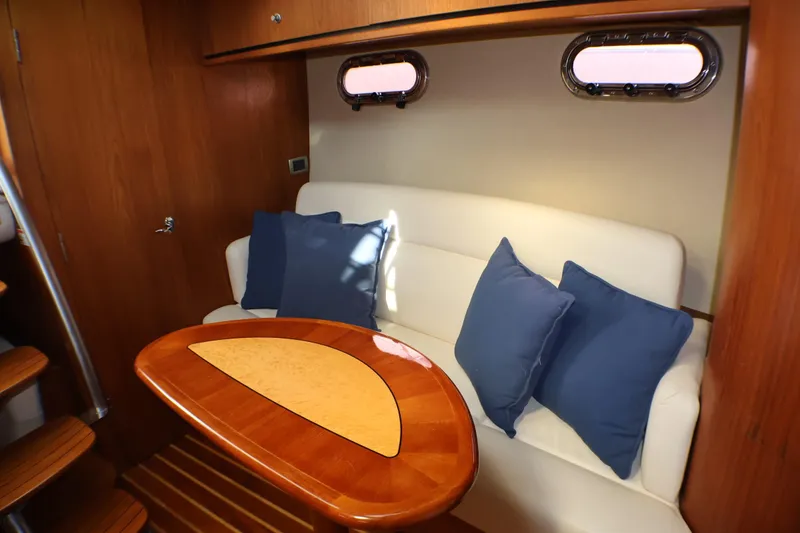 Slide: The Image of 2009 Tiara Yachts 3500 Sovran interior with white seating, wooden table, and blue cushions. - 16
