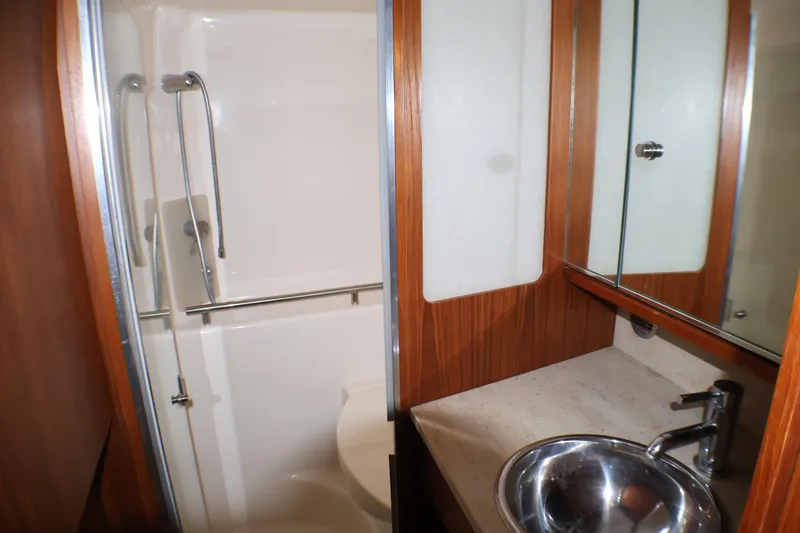 Slide: The Image of 2009 Tiara Yachts 3500 Sovran bathroom with shower, sink, and wooden cabinetry. - 18
