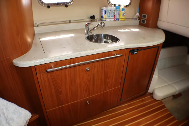 Slide: The Image of 2009 Tiara Yachts 3500 Sovran galley with wooden cabinetry and stainless steel sink. - 24