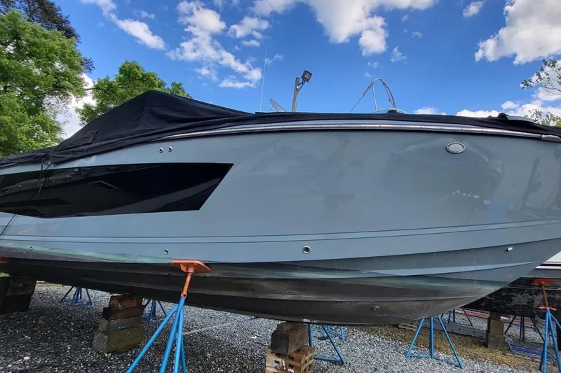 Slide: The Image of 2023 Aviara AV32 OB boat on stands, covered, under a blue sky. - 5