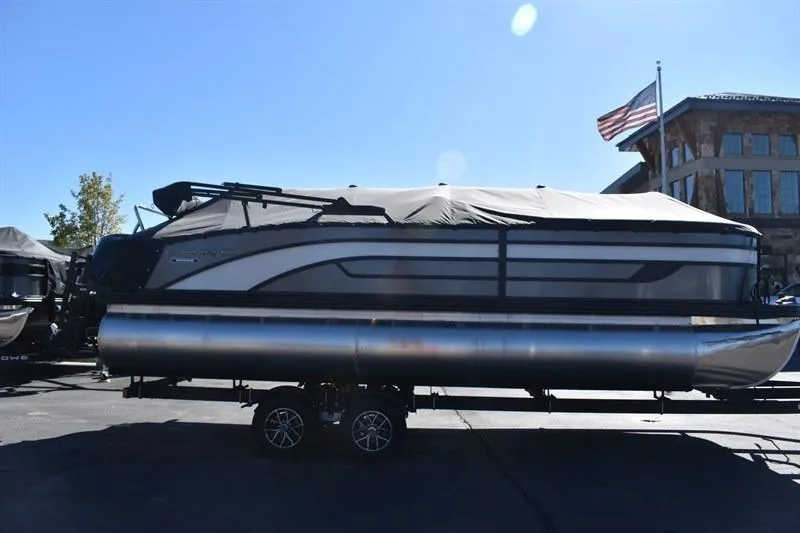 Slide: The Image of 2026 Lowe SF 232 WT Sport Fish pontoon boat on trailer, covered and parked outdoors. - 4