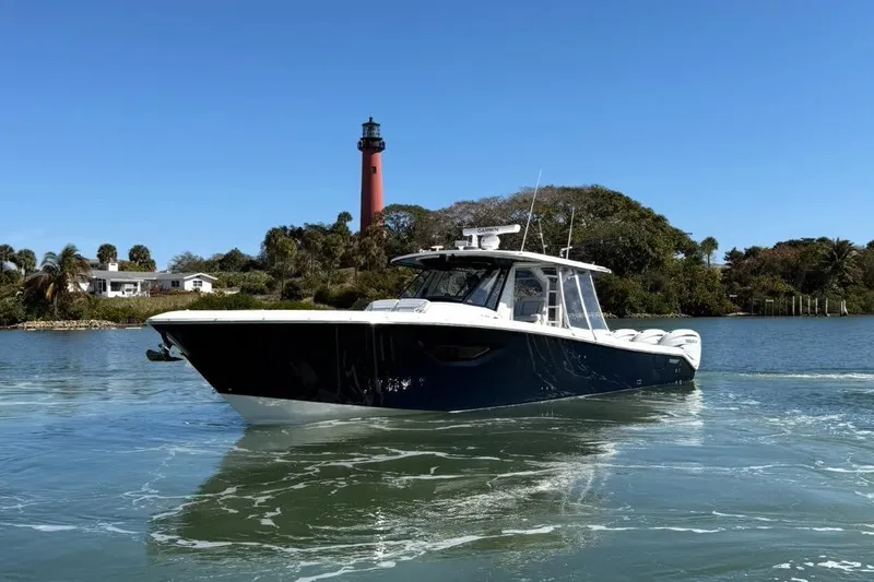 Slide: The Image of 2023 Pursuit S 428 Sport boat near lighthouse and coastal scenery. - 2