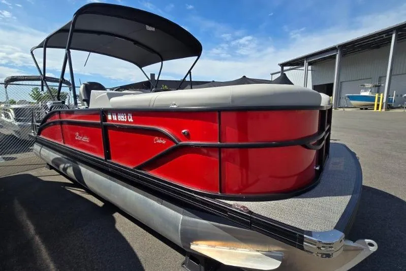 The Image of 2024 Barletta C22UC pontoon boat with red exterior, parked outdoors under blue sky. - 1