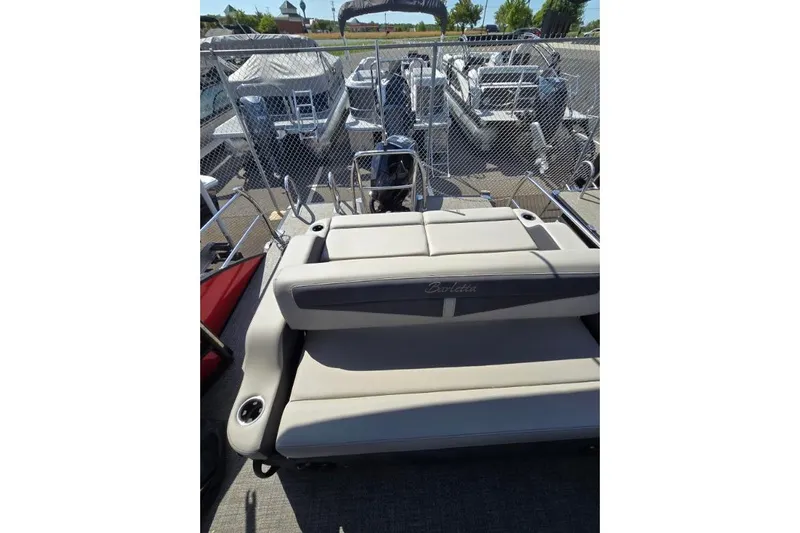 Slide: The Image of 2024 Barletta C22UC pontoon boat with beige seating, docked near other boats. - 5