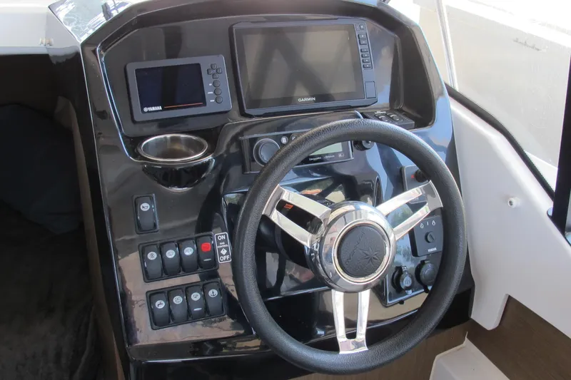 Slide: The Image of 2020 Jeanneau NC 795 boat dashboard with steering wheel and navigation controls. - 15