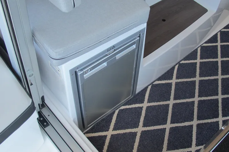 Slide: The Image of Interior of 2020 Jeanneau NC 795 boat with compact fridge and cushioned seating. - 22