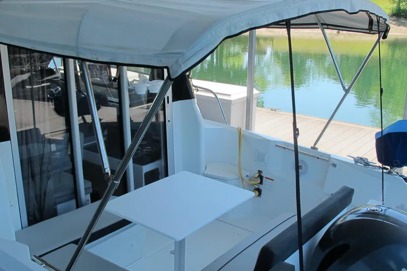 Slide: The Image of 2020 Jeanneau NC 795 boat interior with canopy, docked by a serene lake. - 8