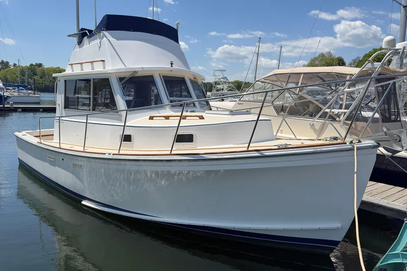 The Image of 1990 Cape Dory 28 Flybridge boat docked at marina under clear blue sky. - 0
